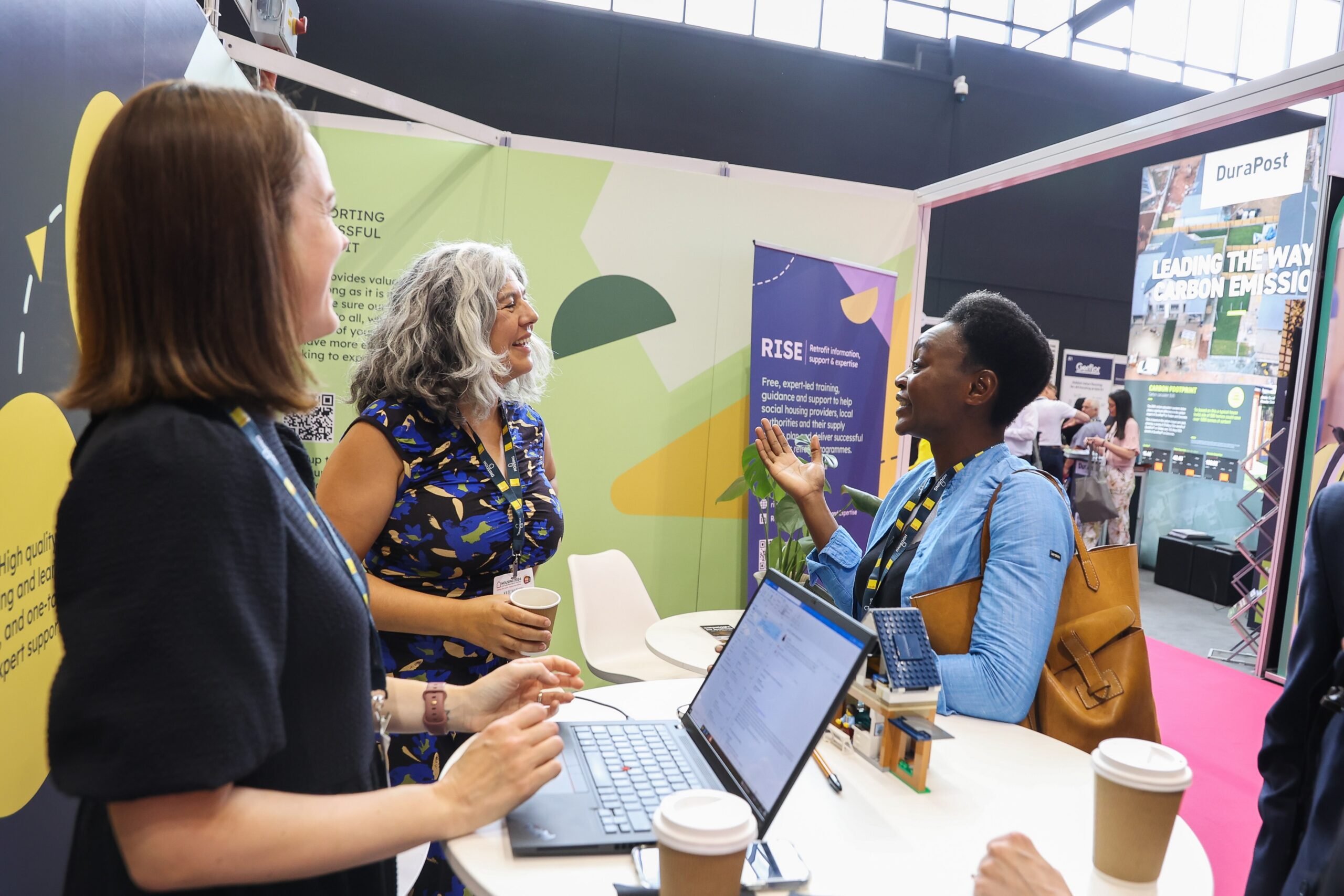 A group of three professional women at a conference discussing a topic in an animated ways.