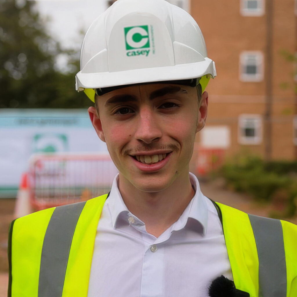Billy wearing a hard hat and high visibility jacket on a building site